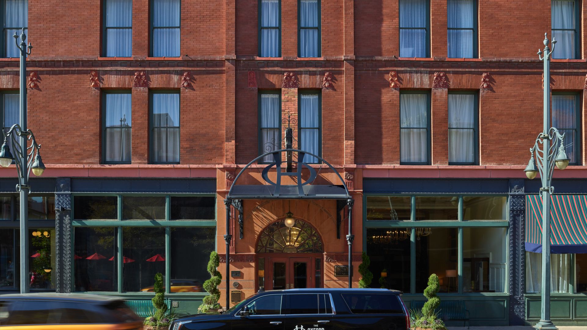 The Oxford Facade - The Oxford branded Cadillac Escalade in front of the historic Red Brick Building