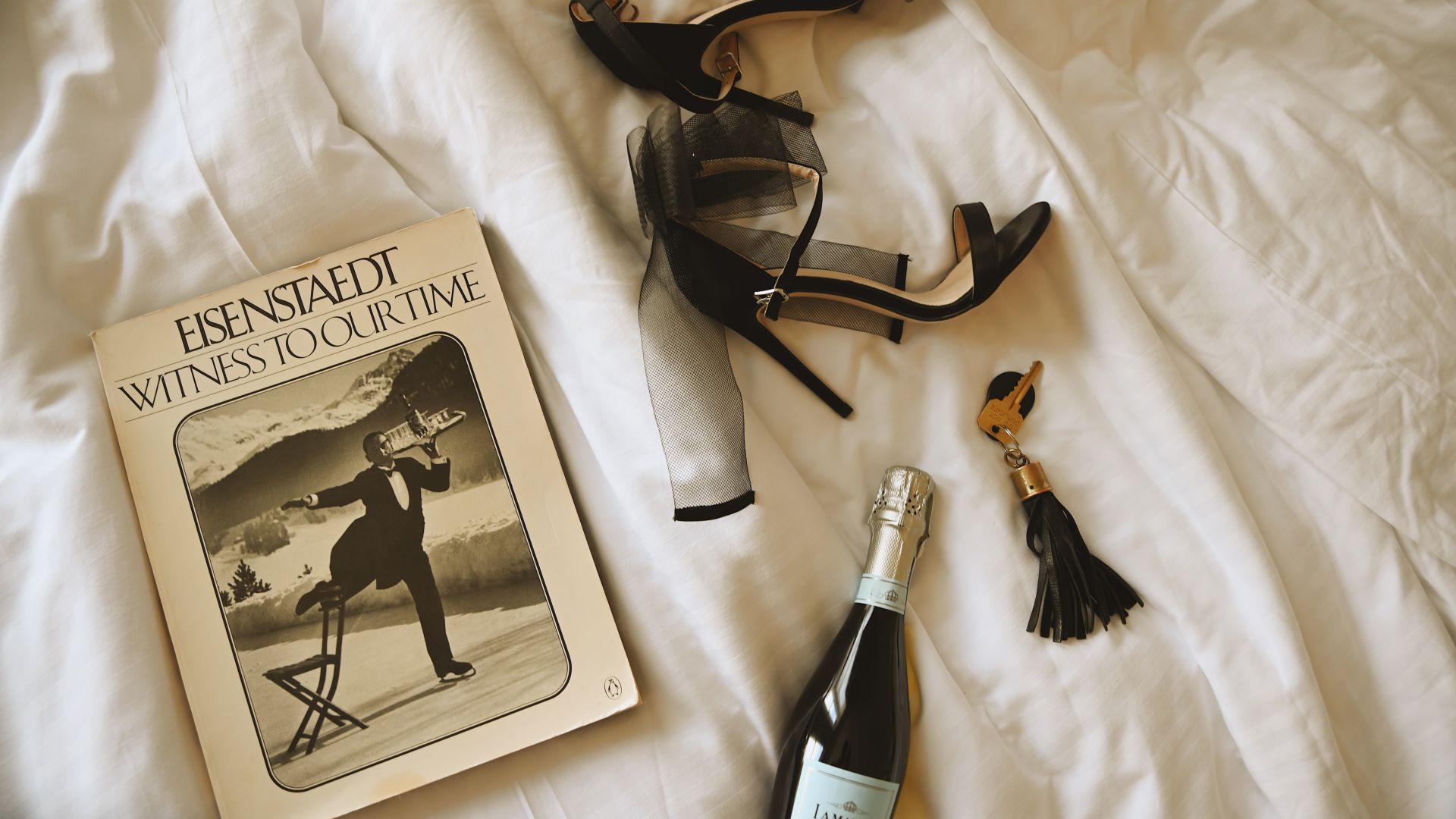 A Book And A Bottle Of Wine On A Bed