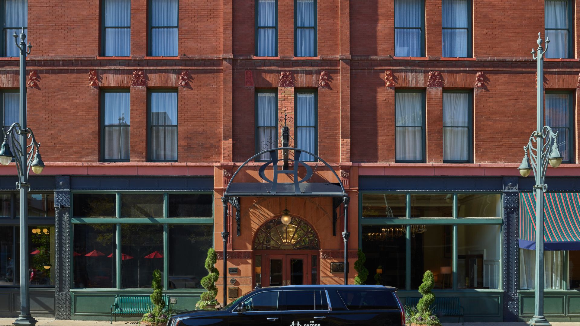 The Oxford Facade - The Oxford branded Cadillac Escalade in front of the historic Red Brick Building